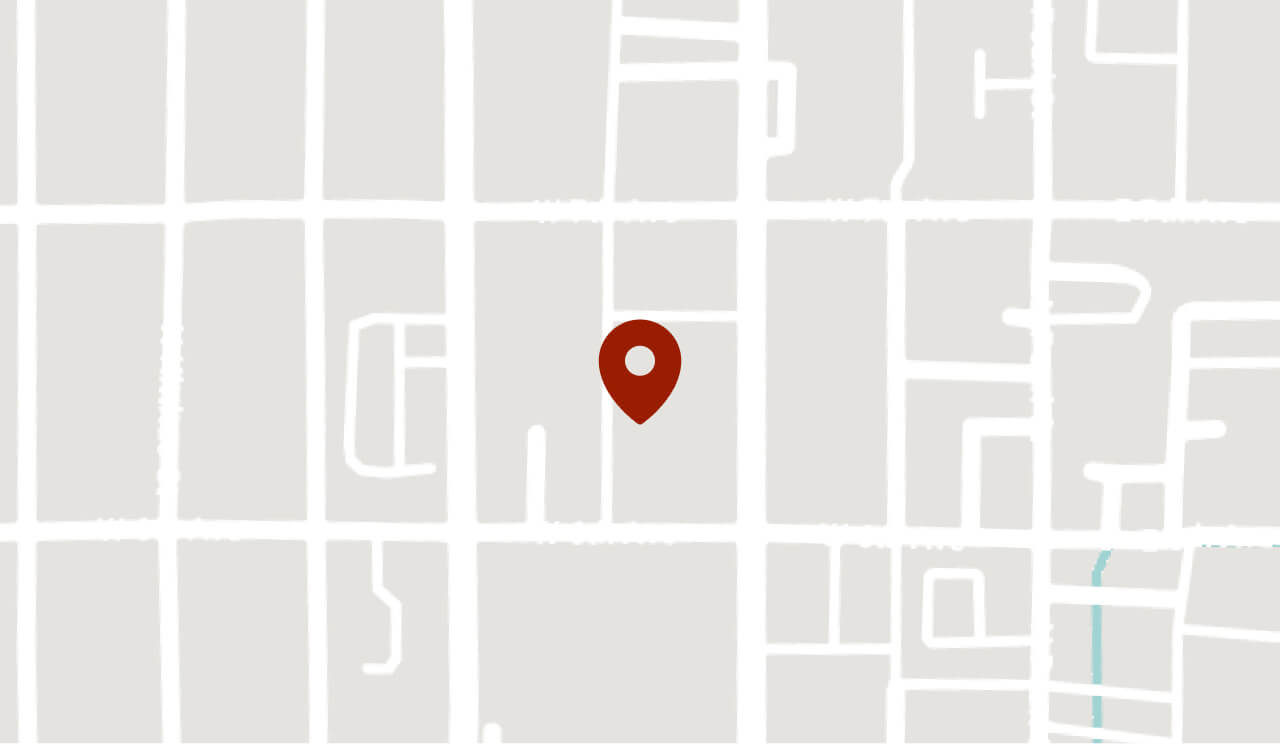 A simple map with white grid lines and a red location pin marker in the center.