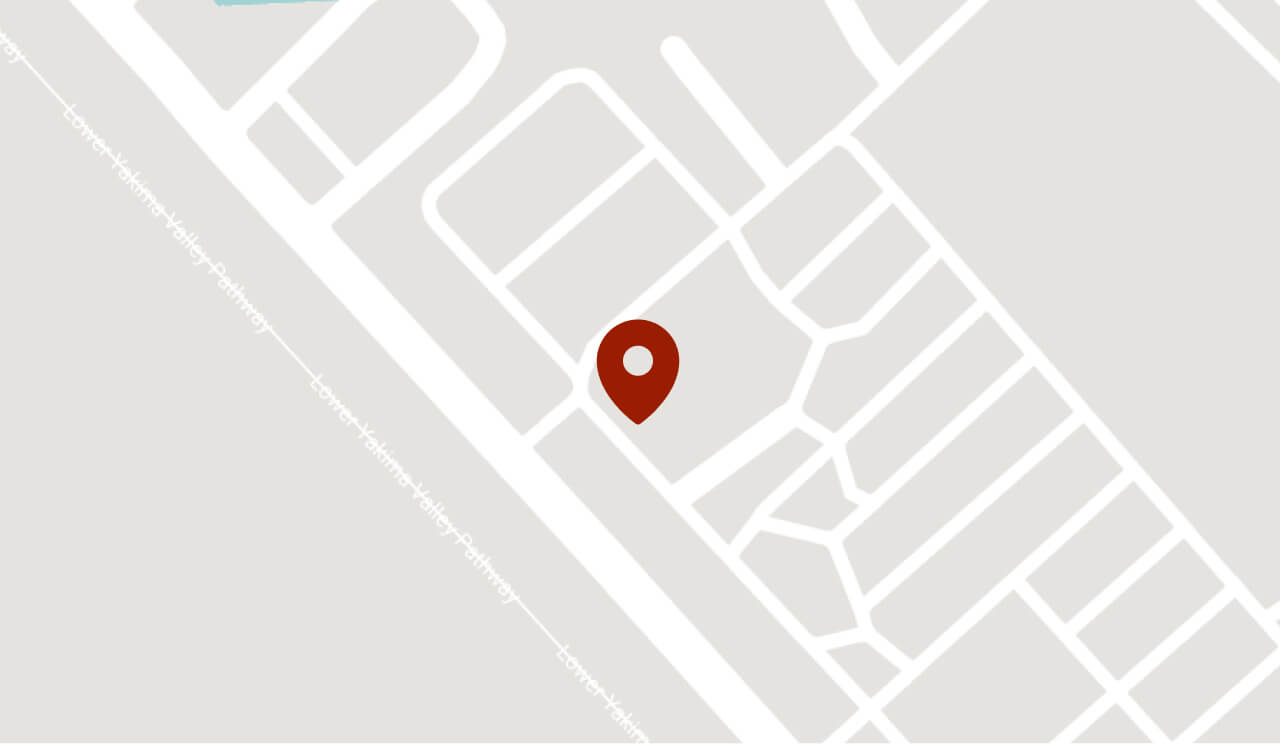 A red location pin marks a specific spot on a simplified, gray-and-white map with outlined buildings and streets.