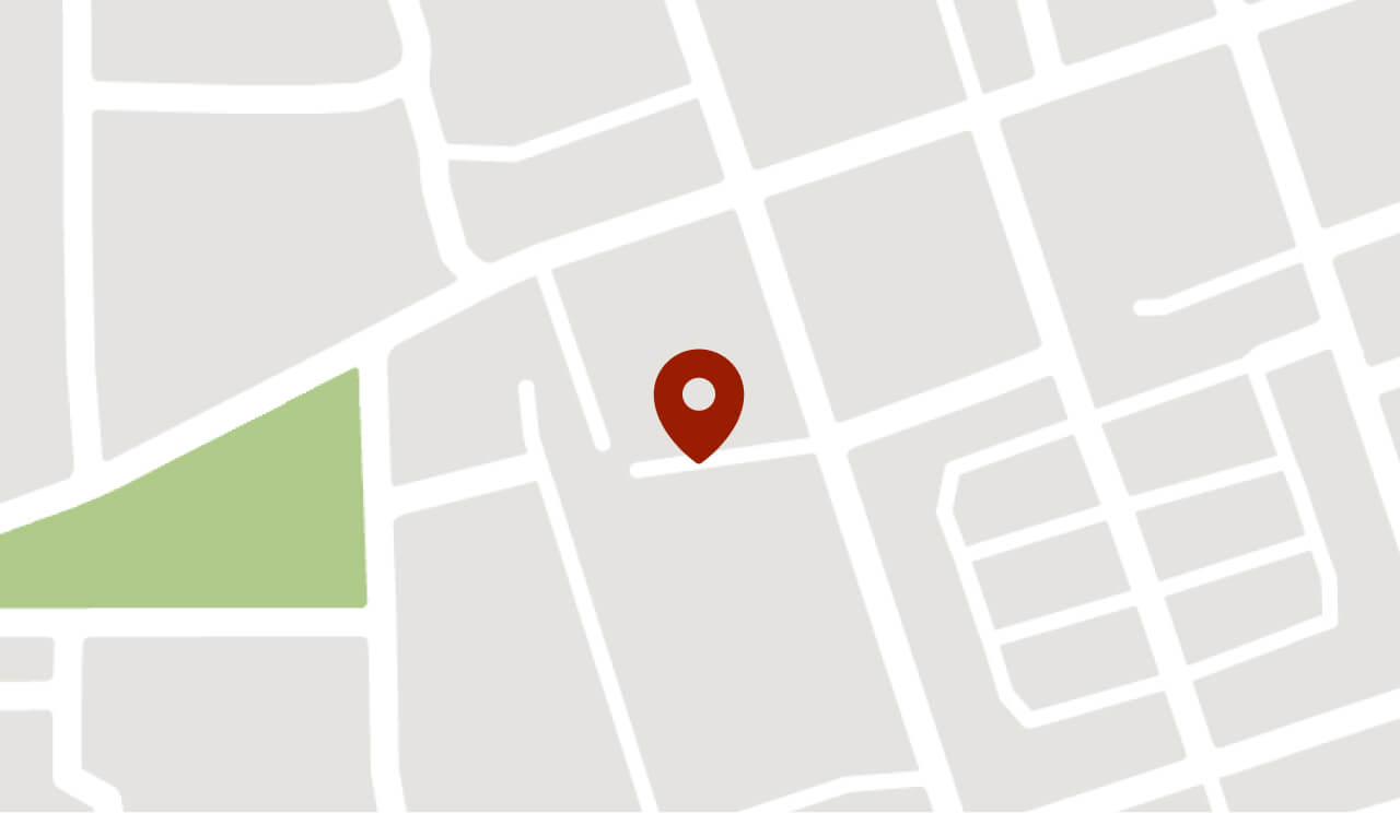 A simplified map with gray streets, a green park area, and a red location pin marking a specific spot near the center.