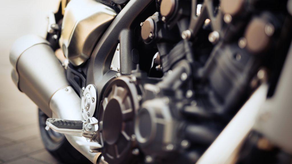 Close-up view of a motorcycle engine and exhaust system, showing mechanical parts and metallic surfaces in detail.